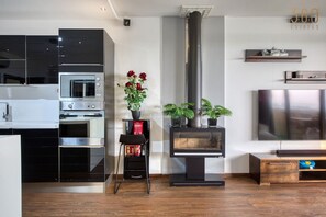 A modern kitchen with built-in appliances, a fireplace, and a television. - Astonishing Terrace Penthouse near the Three Cities (Żabbar)