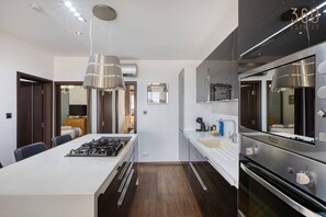 Eine moderne Küche mit einer zentralen Kochinsel, Edelstahlgeräten und einem Essbereich mit Tisch und Stühlen.