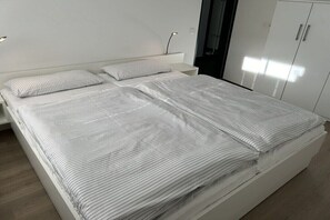 A modern bedroom with a large bed, two bedside tables, and a wardrobe. - Holiday apartment with 2 bedrooms (Greetsiel)