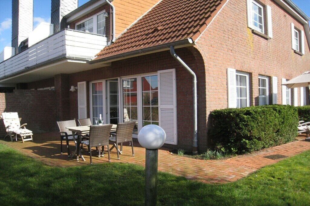 A brick house with a covered patio, outdoor furniture, and a hedge.