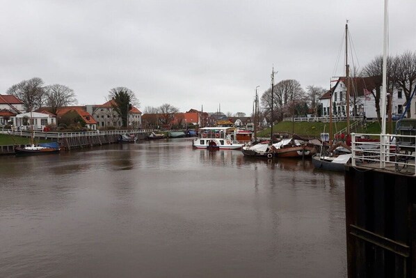 Une rivière paisible où sont amarrés des bateaux, bordée de bâtiments aux toits rouges.