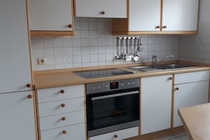 Eine Küche mit weißen Schränken, einer Spüle, einem Einbauofen und einer Arbeitsplatte mit Dunstabzugshaube.