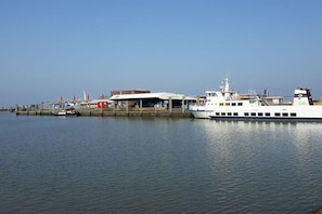 A docked boat with a covered structure, calm water, and a clear sky. - Holiday home in the North Sea with 3 bedrooms (Wittmund - Carolinensiel)