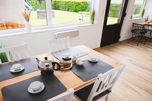 A dining area with a table set for tea, a radiator, and a view of the garden. - Holiday apartment with 1 bedroom (Aurich)