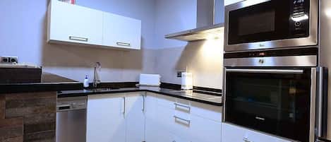 A modern kitchen with stainless steel appliances, white cabinetry, and a dishwasher.