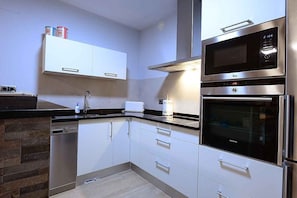 Una cocina moderna con electrodomésticos de acero inoxidable, armarios blancos y lavavajillas.