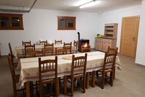 Un comedor con una mesa larga, sillas de madera y un estufa de leña.