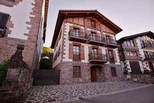 A multi-story building with balconies, stone facade, and a cobblestone street.
