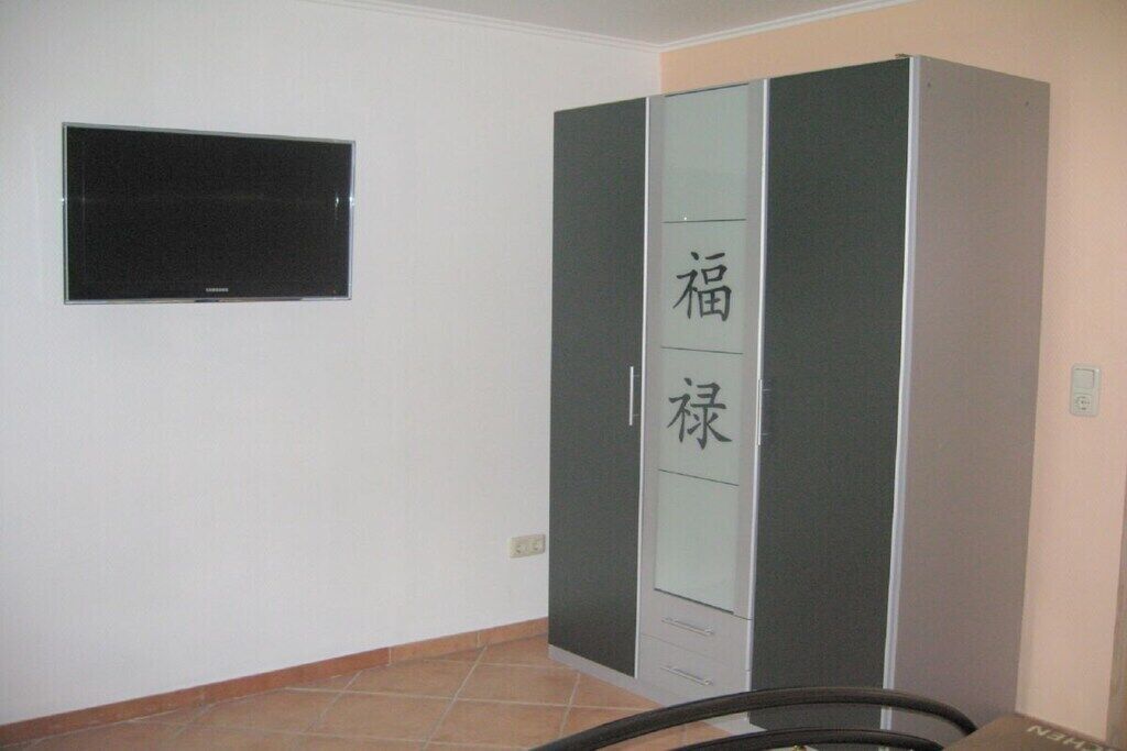 Una habitación con armario, televisor y suelo de baldosas.