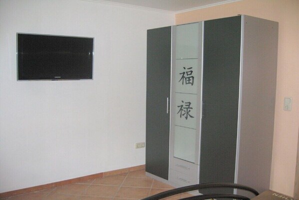 Una habitación con armario, televisor y suelo de baldosas.