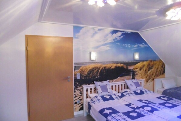 A bedroom with a bunk bed, a mural of a beach scene, and a door.