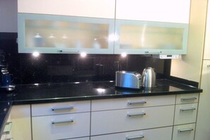 Una cocina moderna con encimeras negras, armarios blancos y electrodomésticos de acero inoxidable.