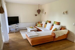 Een woonkamer met een bank, een salontafel, een televisie en een radiator.