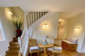 A staircase with a white balustrade leading to a landing with a round table and two wicker chairs. - Holiday home with 3 bedrooms (Grünendeich)