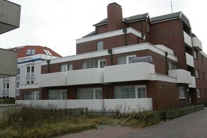 A multi-story building with a flat roof, large windows, and a brick facade. - Holiday apartment with 1 bedroom (Wangerooge)