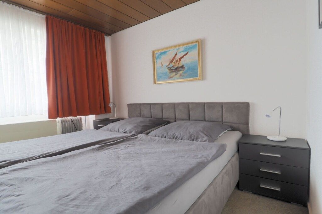 Une chambre à coucher avec un lit, une table de chevet, une lampe et un tableau au mur.