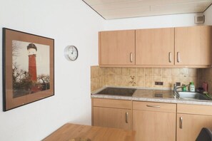 Een keuken met houten kastjes, een spoelbak en een klok aan de muur.