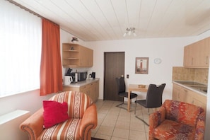 A compact living space with a kitchenette, a dining area, and a seating area with two sofas. - Holiday apartment with 1 bedroom (Wangerooge)