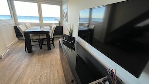 Ein Essbereich mit Meerblick, einem Flachbildfernseher und einem Tisch mit Stühlen.
