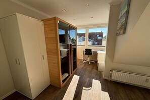 A room with a sliding door closet, a desk with a chair, and a radiator. - Holiday apartment Ostseefee (Schönberger Strand)
