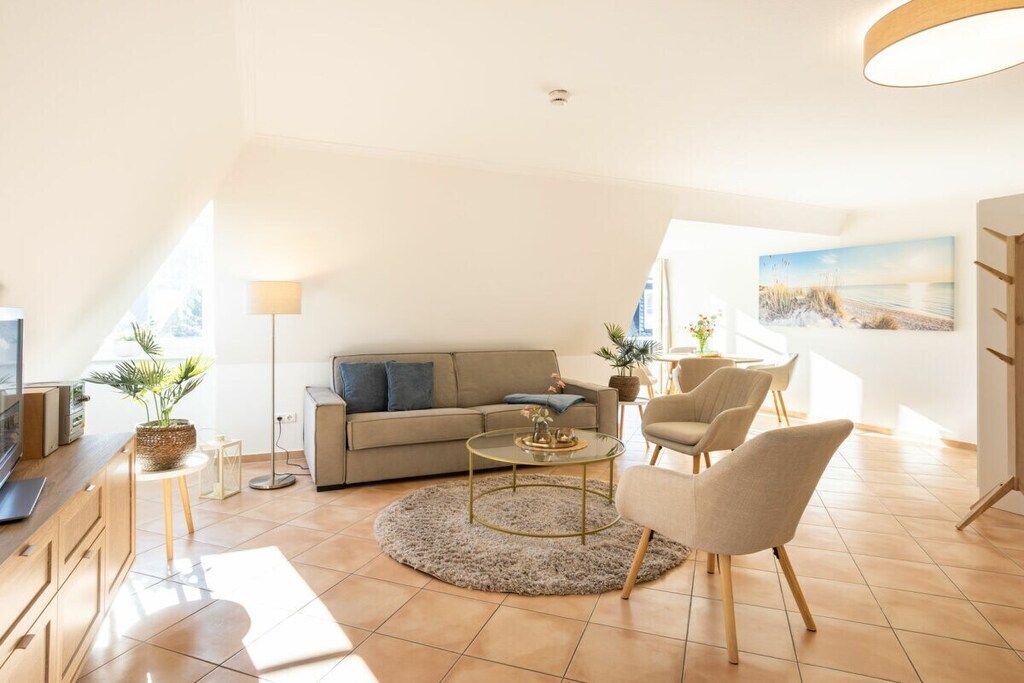 A modern living room with a sofa, armchairs, a coffee table, and a TV.