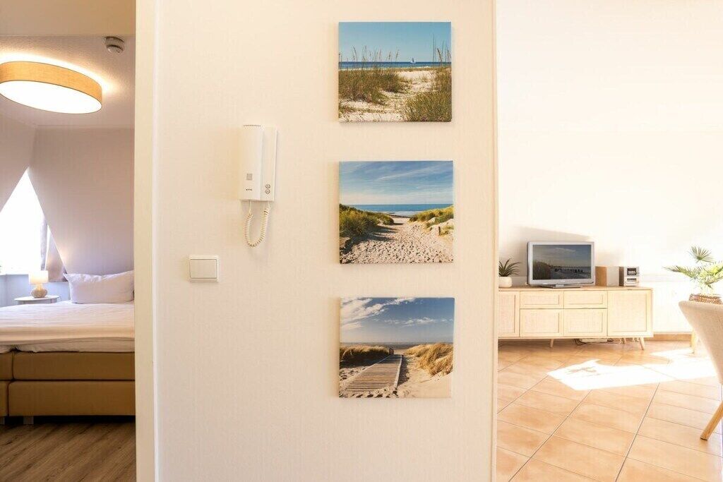 A room with a bed, a bedside table, a wall-mounted phone, and a TV on a cabinet.