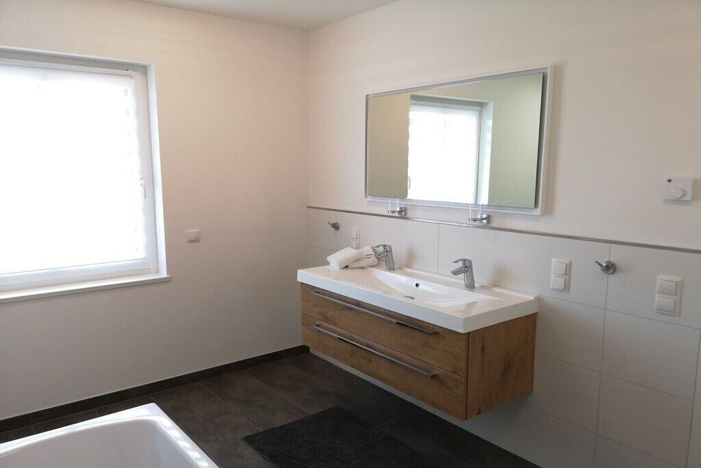 Ein Badezimmer mit weißem Waschtisch, einem großen Spiegel und einer Badewanne.