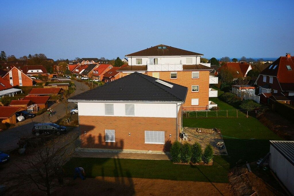 A residential area with houses, a clear sky, and a well-maintained lawn.