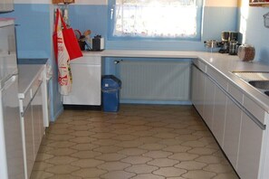 Eine kleine Küche mit weißen Schränken, einem blauen Fenster und einem gefliesten Boden.