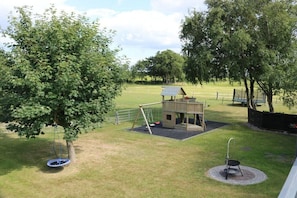 A playground with a swing set, a small wooden playhouse, and a fenced area. - No. 4 on the Doose farm (Büsum)