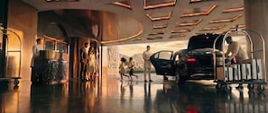 Un hall d’entrée moderne avec un plafond haut, un comptoir d’accueil et un chariot à bagages.