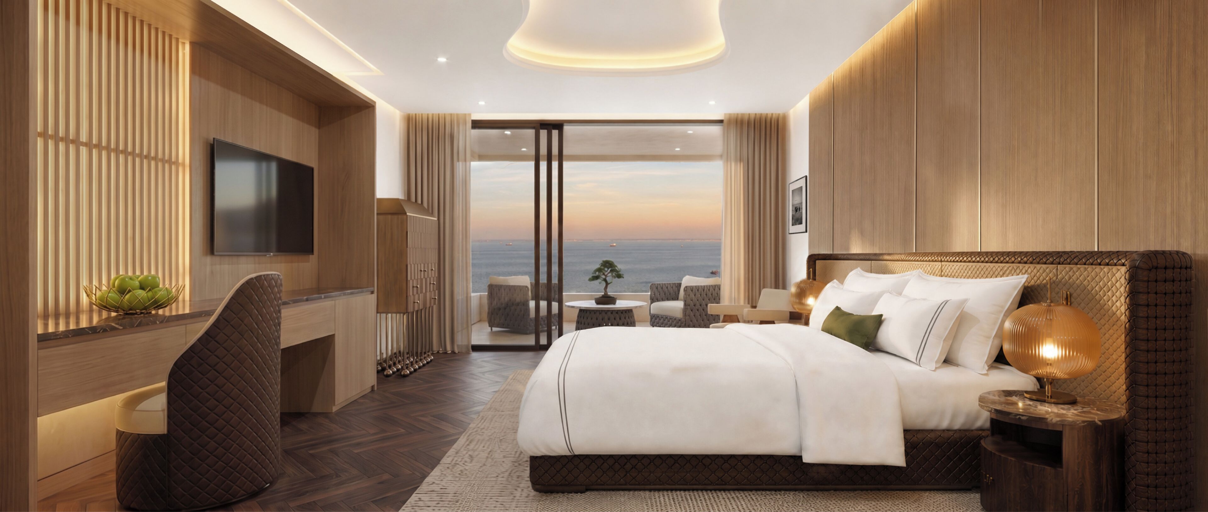 A modern hotel room with a large bed, a TV, a desk, and a view of the sea.