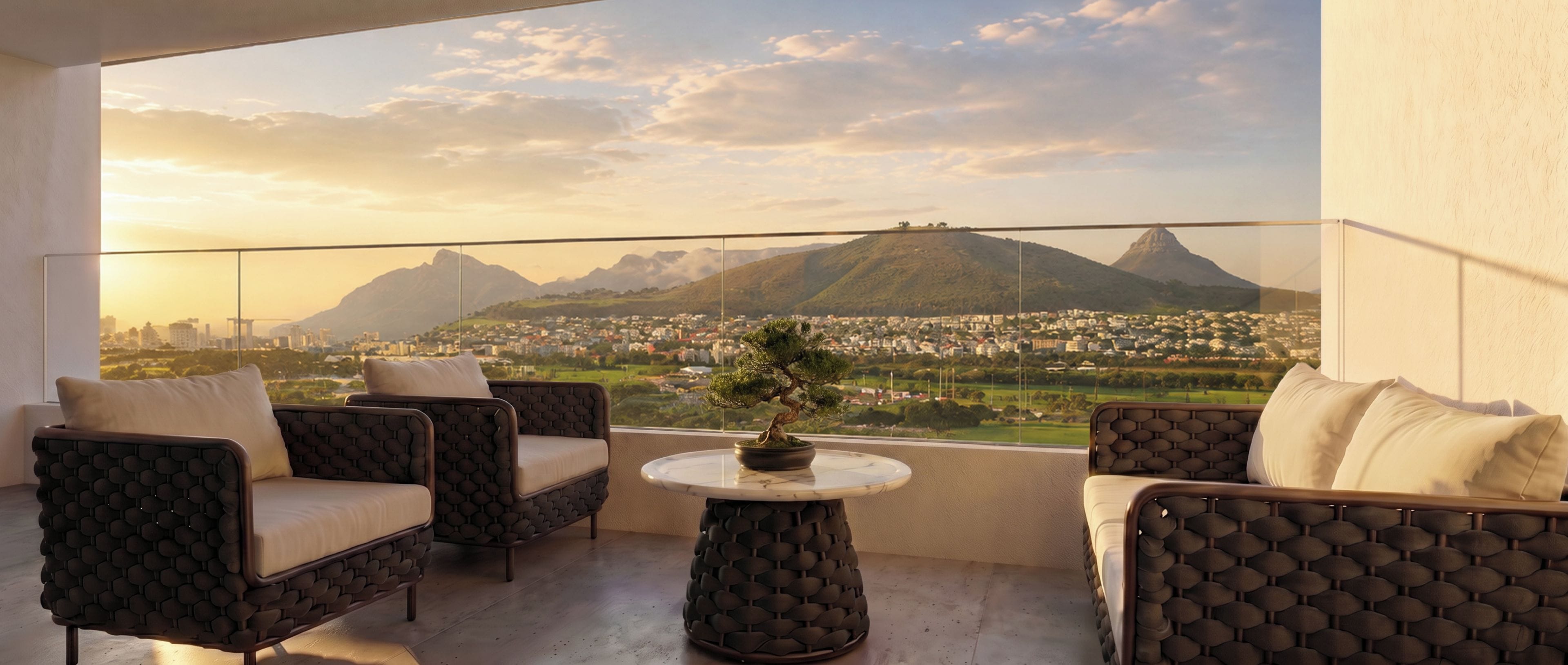 A balcony with two sofas and a small table, overlooking a cityscape with mountains.