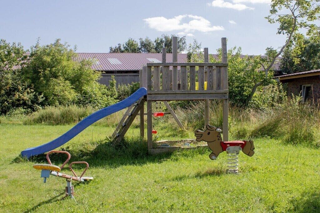 A playground with a slide, a climbing structure, and a seesaw.