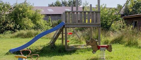 A playground with a slide, a climbing structure, and a seesaw.