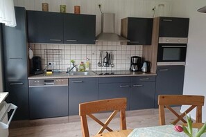 Eine moderne Küche mit dunklen Schränken, einem Geschirrspüler, einer Kaffeemaschine und einem Herd.