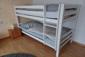 Ein Etagenbett mit zwei Schlafstellen, ein Nachttisch mit Lampe und ein Holzboden.