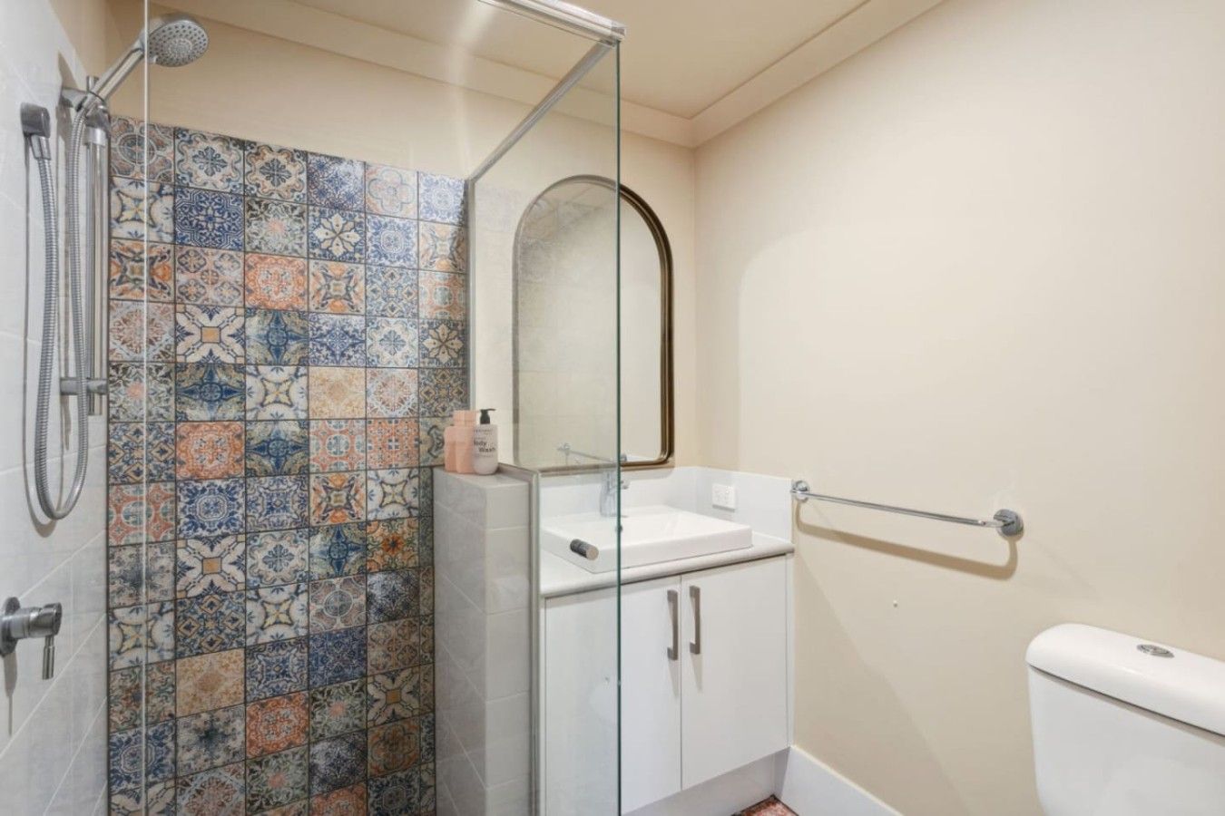 A bathroom with a shower, a sink, a toilet, and a mirror.