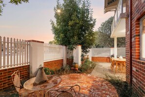 A patio with a brick floor, a round table, and chairs. - Terra de Sol | Terracotta Courtyard, Swan Valley (Bassendean)