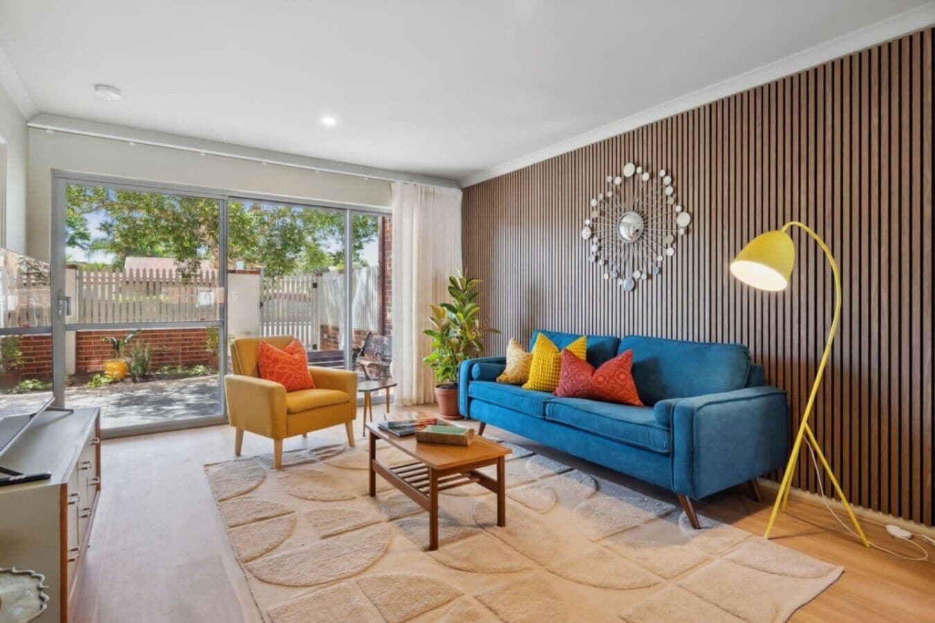 A modern living room with a blue sofa, a yellow armchair, and a coffee table.