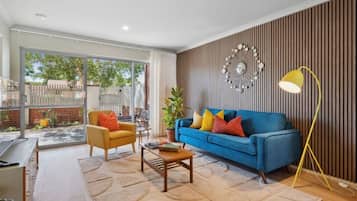 A modern living room with a blue sofa, a yellow armchair, and a coffee table.