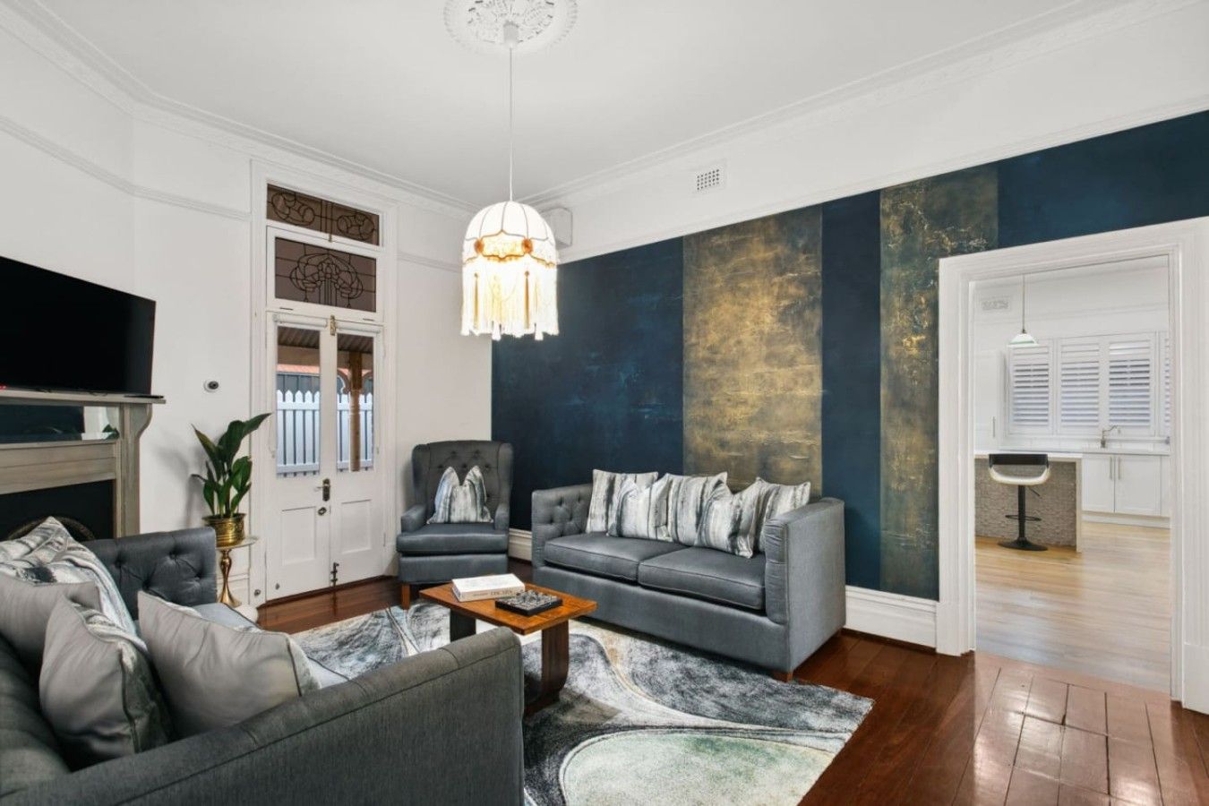Ein Wohnzimmer mit grauem Sofa, Sesseln, einem Couchtisch und einem großen Gemälde an der Wand.