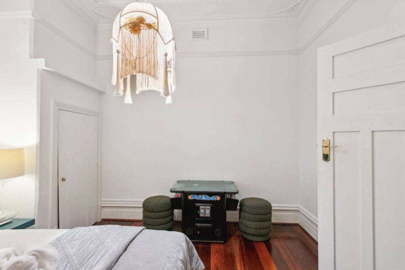 Ein Schlafzimmer mit einem Bett, einem Wanddekor, einem kleinen Tisch mit einem Lautsprecher und zwei grünen Hocker.