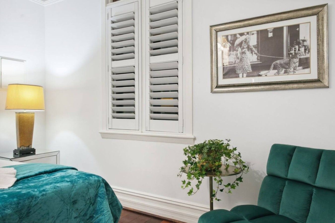 A room with a bed, a lamp, a framed picture, and a green chair.