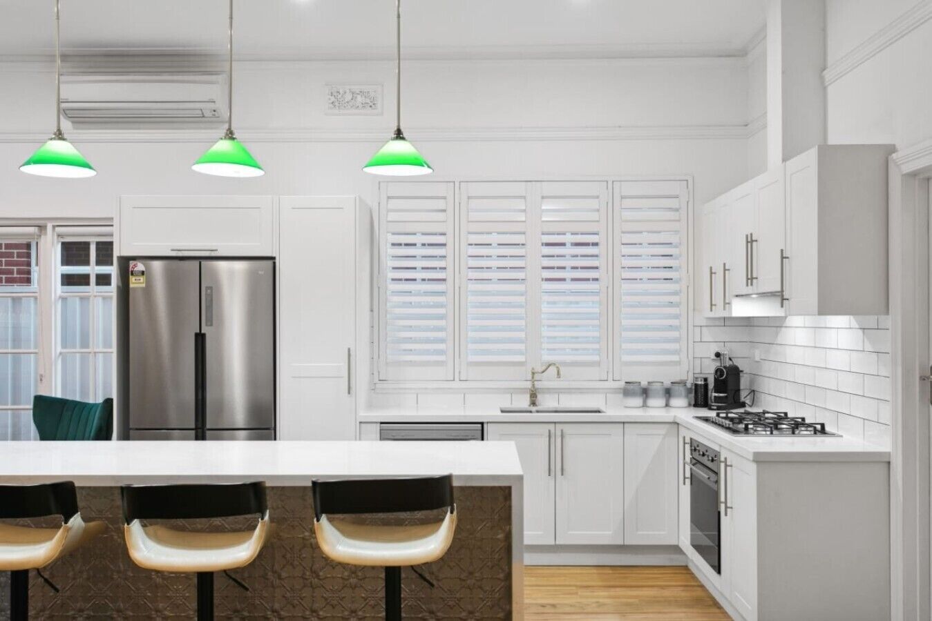 Une cuisine moderne avec des meubles blancs, un réfrigérateur en acier inoxydable, une cuisinière à gaz et un grand îlot central doté de tabourets de bar.
