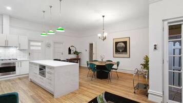 Een ruime keuken met witte kasten, een centraal eiland en een eethoek met een ronde tafel en stoelen.