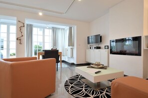 A modern living room with a sofa, a coffee table, and a flat-screen TV mounted on the wall. - Design Apartment Ambiente (Ostseebad Binz)