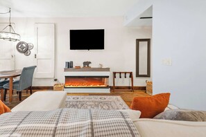 A modern living room with a fireplace, a dining area with a table and chairs, and a television mounted on the wall. - Bliss Retreat Whitefish Studio (Whitefish)