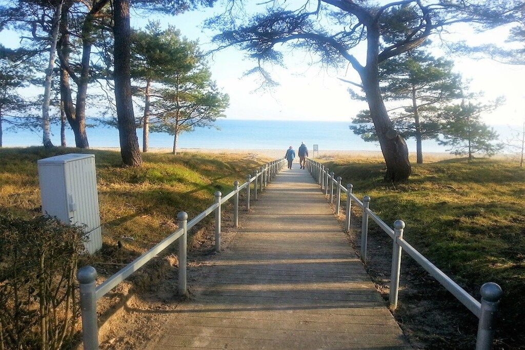 En trägång som leder till en strand, med ett räcke på ena sidan.