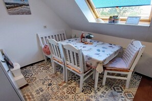 A dining area with a table and chairs, a window with a view, and a patterned floor. - Holiday apartment with 2 bedrooms (Norden)
